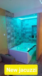 uma banheira num quarto com luzes azuis em Wonderland spa apartment em Niš