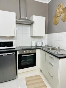 a kitchen with white cabinets and a sink at Kos apartament 1 in Walton on the Hill
