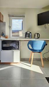 a kitchen with a table and a blue chair at Charmant Studio Cosy in Plaisance-du-Touch