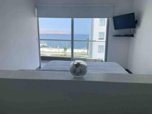 a soccer ball on a bed in a room with a window at Departamento Paracas vista al mar in Paracas