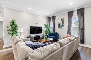 a living room with a large couch and a tv at Spacious Fully Furnished Apartment by Logan Airport in Boston