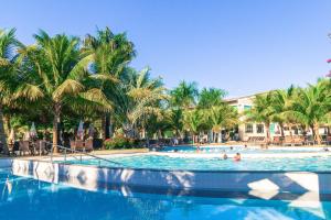 a swimming pool with palm trees and people in it at Lacqua Diroma Apartment in Caldas Novas