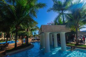 a swimming pool with a gazebo and palm trees at Lacqua Diroma Apartment in Caldas Novas