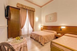 ローマにあるホテル マルティーニのベッド2台とテーブルが備わるホテルルームです。
