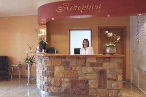 a woman standing at a reception counter in a room at Landhotel Hauer in Pleisweiler-Oberhofen