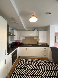 a kitchen with white cabinets and a black and white rug at Beautiful 1 -Bed Apartment in Ferry Village/Renfrew in Renfrew
