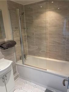 a bathroom with a shower with a tub and a sink at Luxury 3 bedroom house -Private parking, sleeps 6, & featuring en-suite master bedroom in Birmingham