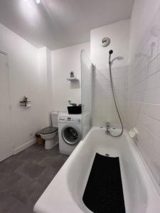 La salle de bains blanche est pourvue d'un lave-linge et d'une baignoire. dans l'établissement Charmant T1, parking privé, proche gare, à Moulins