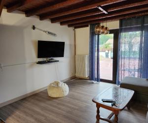 uma sala de estar com uma televisão, um sofá e uma mesa em LA VILLA MONTA em Vendays-Montalivet