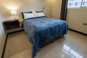 1 dormitorio con 1 cama con manta azul y ventana en Amplia Casa Hogareña, en El Adelanto