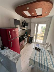 eine kleine Küche mit einem roten Kühlschrank und einem Tisch in der Unterkunft Appart S plus 2 à Sousse zone touristique in Sousse