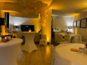 uma sala de jantar com mesas brancas e cadeiras brancas em Les Suites de la Comtesse em Cambrai
