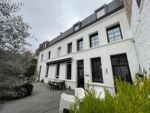 a white building with black windows and a table at Les Suites de la Comtesse in Cambrai