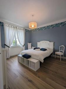 a bedroom with a large bed and a chair at La Villa Voie Verte in Riorges