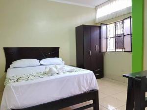 um quarto com uma cama grande e lençóis brancos em Hostal Los Helechos Tarapoto em Tarapoto