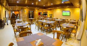 un restaurant avec des tables et des chaises et une télévision dans l'établissement Hotel Fazenda China Park, à Domingos Martins