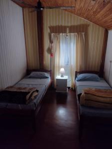 twee bedden in een kleine kamer met een raam bij Casa céntrica in Oberá