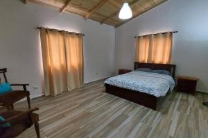 a bedroom with a bed and a wooden floor at Cabaña vista a las montañas de manabao in Manabao