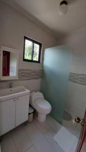 a bathroom with a toilet and a sink and a window at Cabaña vista a las montañas de manabao in Manabao
