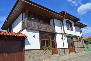 a white house with a balcony on a street at Guest House Stara Planina in Kalofer