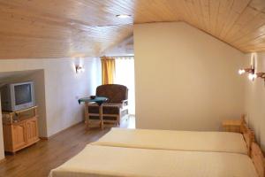a bedroom with two beds and a tv in it at Guest House Stara Planina in Kalofer
