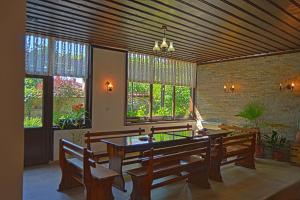 a dining room with a table and benches and windows at Guest House Stara Planina in Kalofer