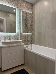 a bathroom with a tub and a sink and a mirror at MODERN MINIMALIST APARTMENT Close to Airport and City Center. in Chişinău