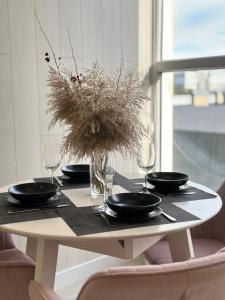 a table with plates and glasses and a vase with flowers at MODERN MINIMALIST APARTMENT Close to Airport and City Center. in Chişinău