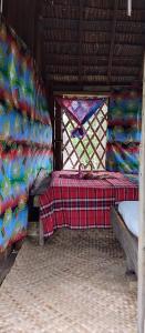 Cette chambre comprend 2 lits et une fenêtre avec une couverture. dans l'établissement Glowing Mountain view tree house, à Loanengo
