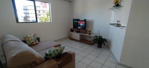 a living room with a couch and a flat screen tv at Praia do Caribessa - Quarto Privativo - Pedacinho do Paraíso in João Pessoa
