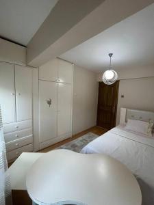 a white bedroom with a bed and a table at Harika ev aileler için in Konak