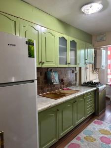 a kitchen with green cabinets and a white refrigerator at Harika ev aileler için in Konak
