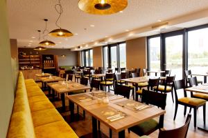 un restaurant avec des tables et des chaises en bois ainsi que des fenêtres dans l'établissement DiMas Hotel Ettenheim - Rust, à Ettenheim