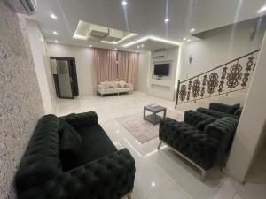 a living room with black couches and a television at شاليهات الأحلام in Rayyis