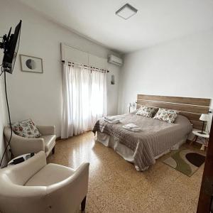 a white bedroom with a bed and a chair at 248 Apartamento in Alta Gracia