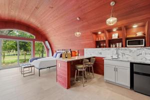 a room with a kitchen and a bedroom with a bed at Unique Tempranillo Wine Barrel Cabin in Fredericksburg +15 photos