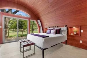 a bedroom with a large bed and a large window at Unique Tempranillo Wine Barrel Cabin in Fredericksburg