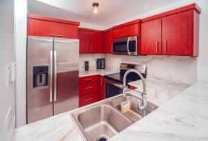 a kitchen with red cabinets and a stainless steel refrigerator at Paradise Coast PR - Condo in Isabela