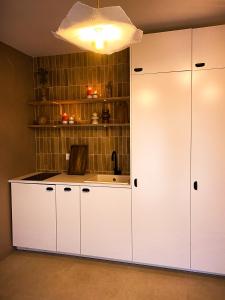 - une cuisine avec des placards blancs et un évier dans l'établissement Love Room Suite Bali - Auray en Bretagne, à Brech