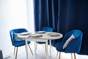 una mesa con sillas azules y una cortina azul en Appartement moderne et lumineux - Centre ville Creil, en Creil