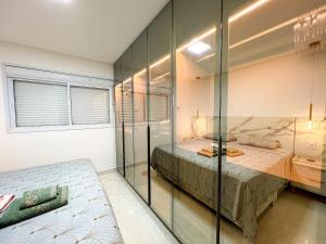 a bedroom with a bed and a glass wall at Apto Moderno c/ Vista Fantástica do Flamboyant in Goiânia