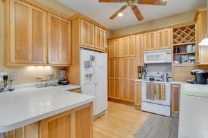 a kitchen with wooden cabinets and white appliances at Eau Claire Retreat Close to Chippewa Riverfront! in Eau Claire