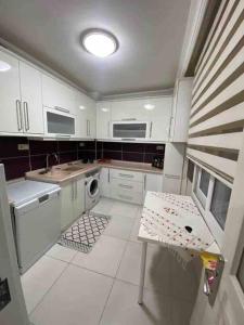 a kitchen with white cabinets and a sink and a table at Ferah ve şık cosy daire in Konak