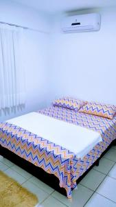 una cama con un edredón encima en Apartamento em Fortaleza, Abolição Mucuripe, en Fortaleza