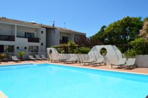 einen Pool mit Liegestühlen und ein Haus in der Unterkunft Hotel L'Oceane in La Cotinière