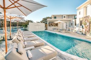 ペレジアンビーチにあるEssence Peregian Beach Resort - Lily 4 Bedroom Luxury Home with Private Poolのラウンジチェアとパラソル付きのスイミングプールを併設しています。