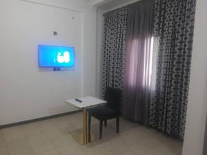 a room with a table and a chair and a television at JAD HOTEL Dschang in Dschang