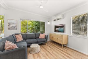 sala de estar con sofá y 2 ventanas en SeaSalt72 by Experience Jervis Bay, en Erowal Bay