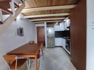 eine Küche mit einem Holztisch und einem Kühlschrank in der Unterkunft Hermoso Apartamento tipo Loft en Lecheria Anzoátegui in El Morro de Barcelona