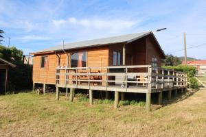 een klein houten huis op een platform in een veld bij Acun Lihuen in Cobquecura